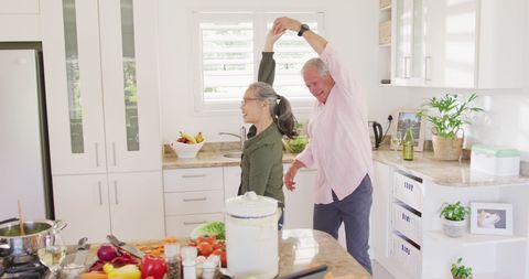 Senior couple joyfully dancing together in bright kitchen
