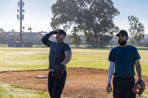 Morning baseball practice two players on infield adjusting cap and holding ball