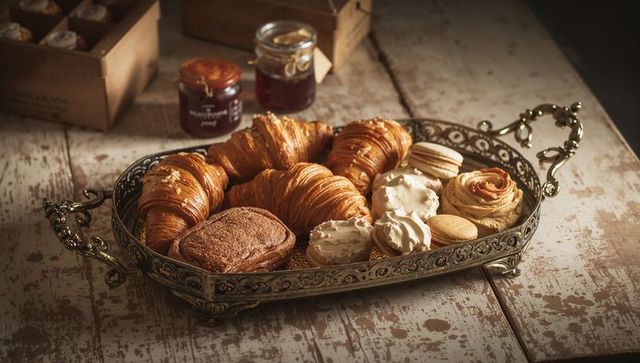Rustic pastry platter showcasing golden croissants, macarons and artisanal confections