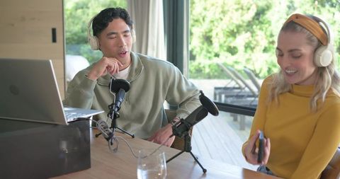 Recording podcast in home studio, two co-hosts collaborating with microphones and laptop