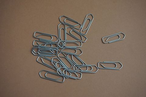 Scattered silver paperclips on brown kraft background for office supply and organization