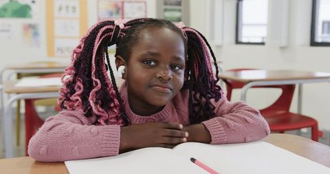 Young student with pink hairstyles studying in classroom