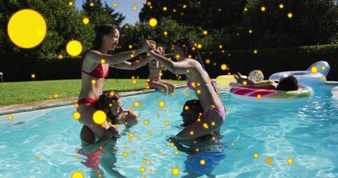 Friends giving shoulder rides in backyard pool during sunny summer party with inflatables