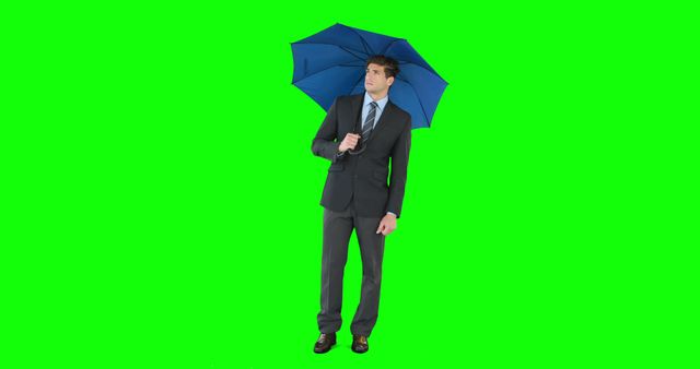 Young businessman sheltering with umbrella on green screen
