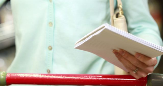 Person Grocery Shopping While Holding Shopping List and Pushing Cart - Download Free Stock Images Pikwizard.com