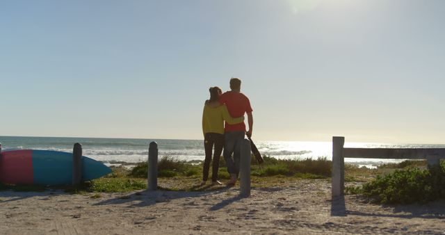 This scene of a couple sharing a moment at the beach during sunset evokes feelings of romance and tranquility. Perfect for use in advertisements for vacation resorts, travel agencies, or greeting cards for anniversaries and romantic occasions.