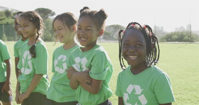 Happy diverse school children wearing green t-shirts with recycling symbol. Education, learning, ecology, environment, inclusivity and school, unaltered.