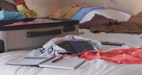 Preparing for travel: passport and boarding pass on bed with suitcase