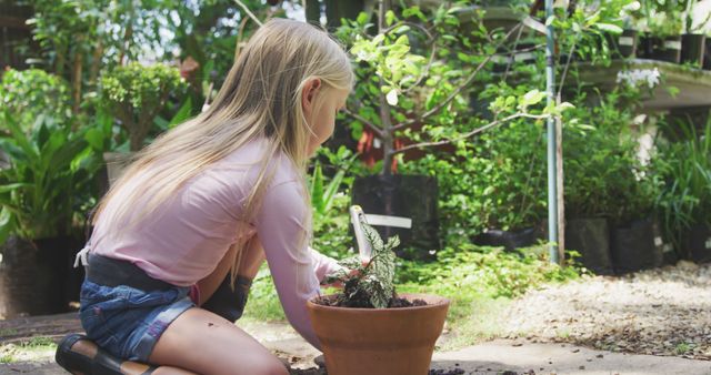 Caucasian girl sitting on ground and planting in flowerpot in garden - Download Free Stock Photos Pikwizard.com