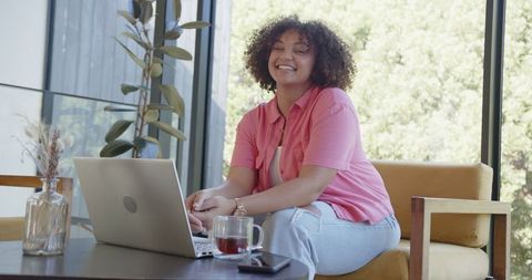 Happy Woman Working on Laptop in Relaxed Green Lounge Area