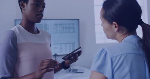 Coworkers Collaborating with Technology at Desk in Modern Office