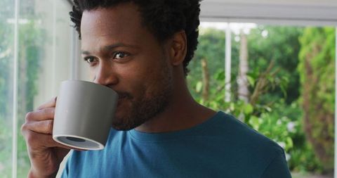 Calm Young Man Drinking Coffee at Home with a Smile