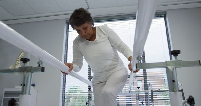 Biracial female patient trying to walk in therapy room. Physiotherapy, treatment, rehabilitation, medical services, healthcare and hospital, unaltered.