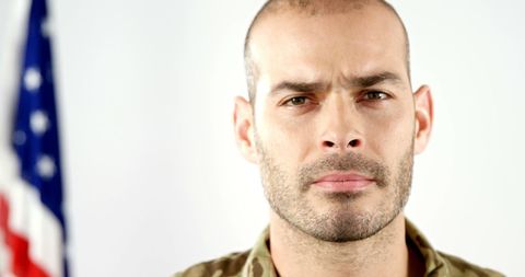 Middle-aged military man before american flag reflecting patriottism