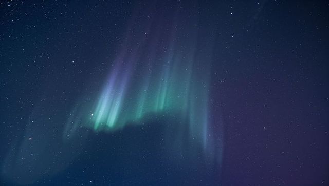 Dancing Aurora Curtains Green and Purple Northern Lights Over Starry Remote Sky