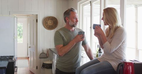 Relaxing Mature Couple Drinking Coffee in Sunlit Kitchen