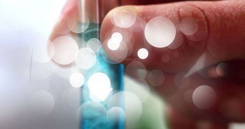 Hand holding test tube with blue liquid in scientific laboratory