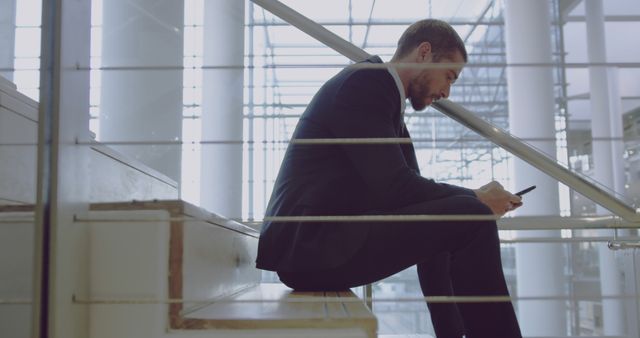 Businessman Sitting on Staircase Typing on Smartphone in Modern Office Building - Download Free Stock Images Pikwizard.com