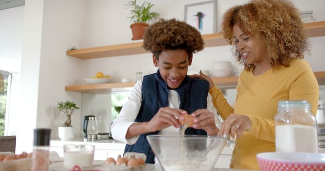 Mother and teenage son bonding while baking in modern kitchen. Useful for articles on family activities, parenting tips, or healthy homemade recipes. Ideal for blogs, newsletters, or advertisements promoting family togetherness, cooking classes, or home products.