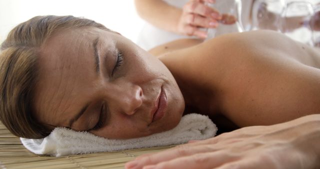 A middle-aged Caucasian woman relaxes during a spa treatment, with a professional gently pouring water over her hands, with copy space. Capturing a moment of tranquility, the image reflects the soothing atmosphere of a wellness or beauty therapy session.