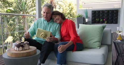 Senior Couple Celebrating Birthday with Cake and Gift on Patio