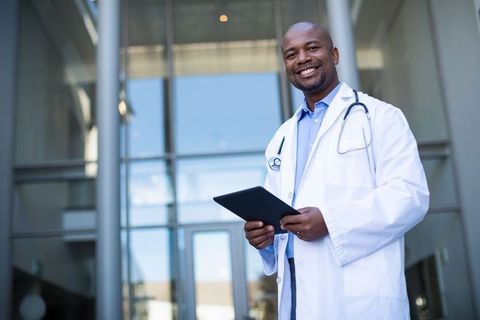 Confident Male Doctor Holding Tablet Outside Hospital