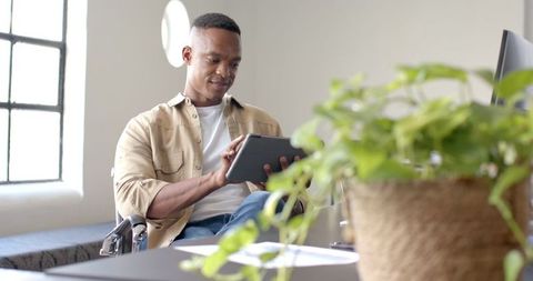 Young Professional Using Tablet in Wheelchair Working in Modern Office