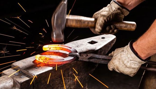 Blacksmith forging glowing horseshoe on anvil, hammer striking sparks, gloved hands shaping metal