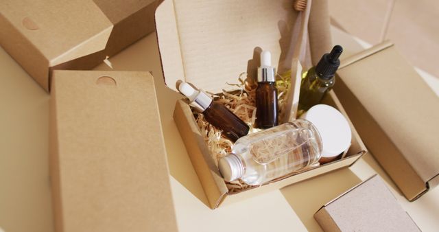 Open cardboard box displaying assortment of skincare products in dropper bottles and glass jars. Ideal for promoting sustainable cosmetics, self-care routines, or eco-friendly packaging options. Perfect image for beauty blogs, green product reviews, and organic product websites.
