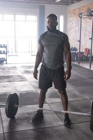 Male athlete preparing deadlift in industrial gym with loaded barbell and brick wall