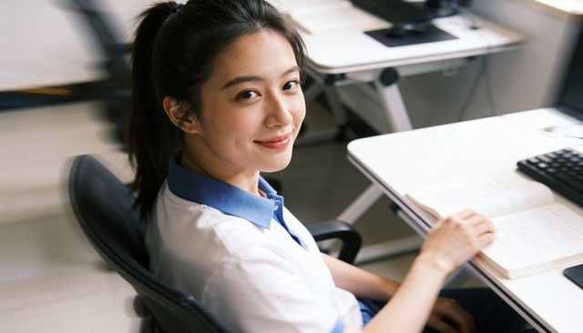 Young student smiling at desk with notebook and keyboard in modern classroom
