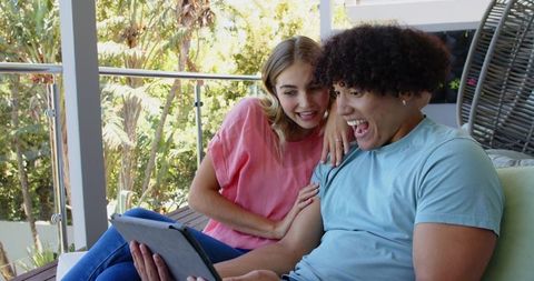 Young Couple Relaxing on Balcony While Watching Tablet