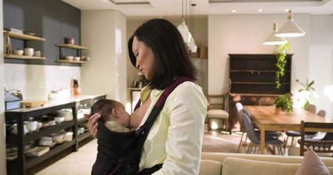 Asian mother breastfeeding baby in cozy home environment