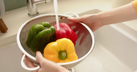Washing Colorful Bell Peppers in Modern Kitchen Sink