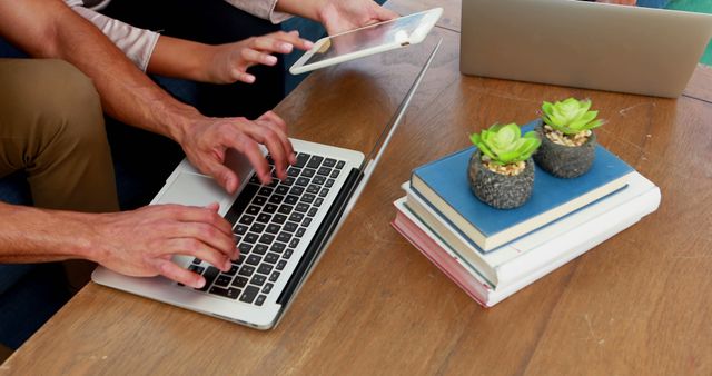 Collaborating with laptops and tablet at workspace with plants and books - Download Free Stock Images Pikwizard.com