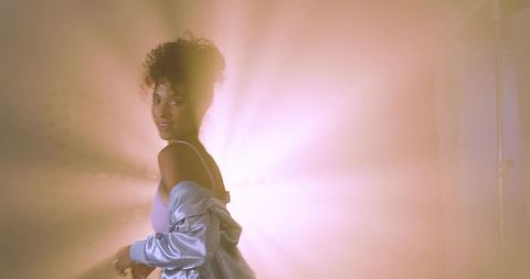 African american woman posing in satin jacket sliding off shoulder backlit pastel glamour