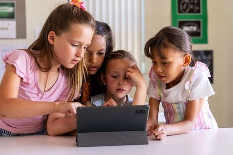 Elementary Girls Collaborating Around Tablet, Sharing Screen and Learning Together