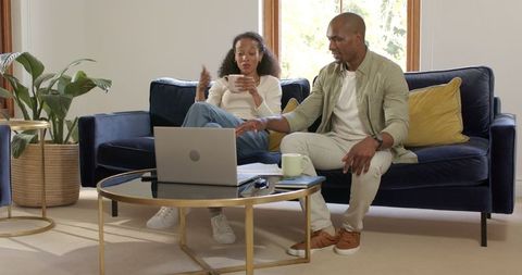 Couple Enjoying Coffee and Conversation at Home with Laptop