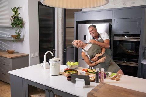 Playful Senior Couple Dancing Together in Modern Kitchen