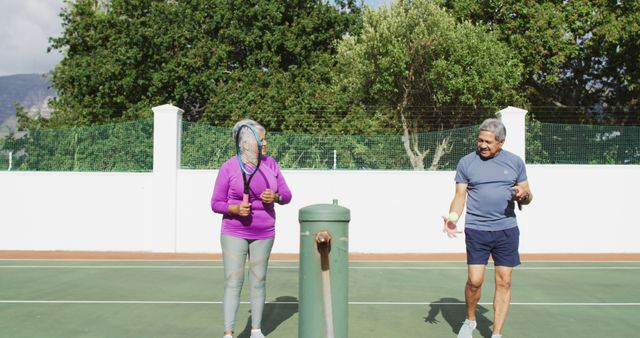 Seniors enjoying a game of tennis outdoors on a sunny day, highlighting active lifestyle and fitness in older age. Useful for promoting sports among the elderly, healthy living campaigns, and community recreation programs.