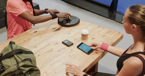 Athletes relaxing after padel game with coffee and gadgets