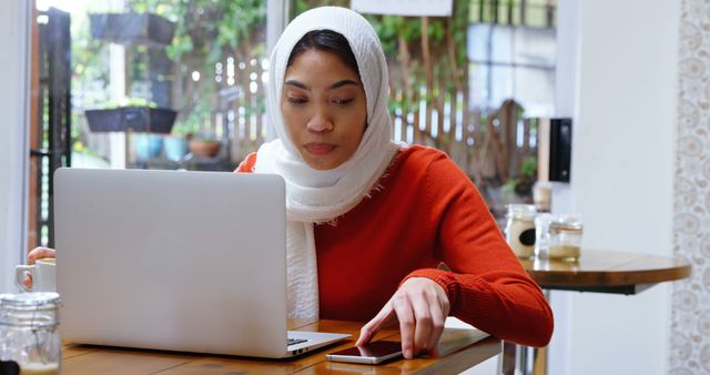 Young Entrepreneur Working on Laptop and Checking Phone in Cozy Cafe - Download Free Stock Images Pikwizard.com