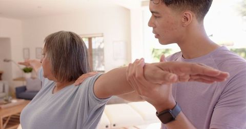 Physiotherapist assisting senior woman with arm stretching in clinic