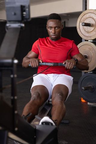Focused Man Rowing on Machine in Modern Gym Setting
