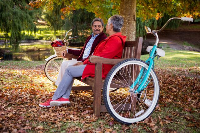 Mature couple relaxing on wooden bench at park during autumn