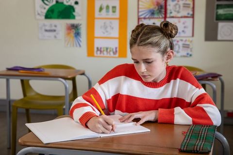 Focused student writing notes in classroom