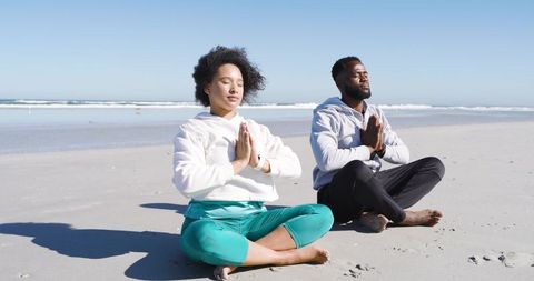 Diverse Couple Meditating on Serene Beach Practicing Yoga and Mindfulness by Ocean