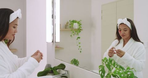 Woman Applying Skincare in Bathroom with Indoor Plants