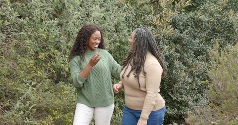 Two African American Friends Walking on Lush Trail Laughing and Talking Outdoors