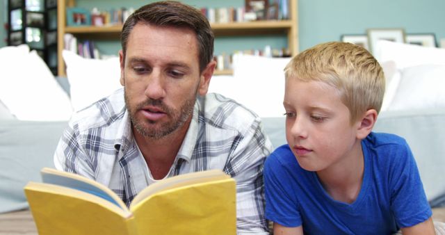This depicts a father engaging in storytelling with his young son, enhancing their bond and spending quality family time in a cozy home environment. The setup suggests a nurturing and educational activity that promotes reading and literacy. This can be used for advertisements, articles, or educational content focusing on family activities, parent-child relationships, and the importance of reading.